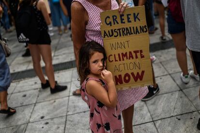 Una niña junto a un cartel en el que se puede leer "Griegos y australianos quieren pasar a la acción contra el cambio climático ya" en Atenas esta mañana. 