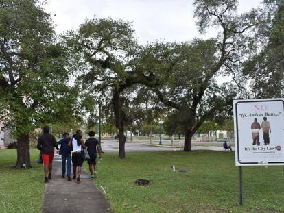 Un grupo de jóvenes pasea cerca de un cartel de prohibición de pantalones caídos en Opa-locka (Florida).