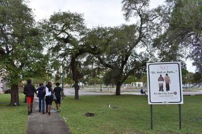 Un grupo de jóvenes pasea cerca de un cartel de prohibición de pantalones caídos en Opa-locka (Florida).