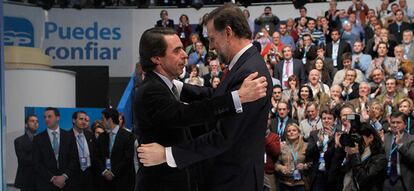 Aznar y Rajoy se saludan en el escenario de la convención de Partido Popular.