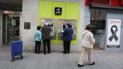Personas mayores sacan dinero en un cajero de Bankia durante el inicio de la semana octava del estado de alarma decretada por la crisis del coronavirus
