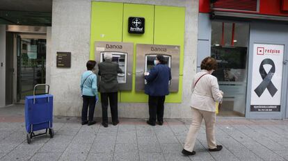 Personas mayores sacan dinero en un cajero de Bankia durante el inicio de la semana octava del estado de alarma decretada por la crisis del coronavirus