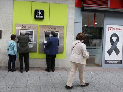 Personas mayores sacan dinero en un cajero de Bankia durante el inicio de la semana octava del estado de alarma decretada por la crisis del coronavirus