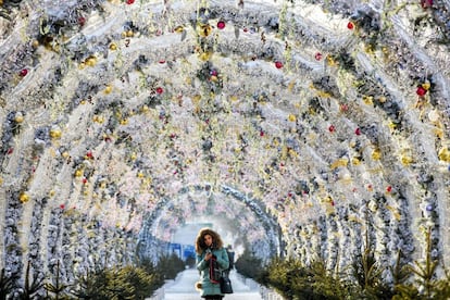 Una mujer camina por un túnel decorado con luces navideñas, en el centro de Moscú (Rusia).