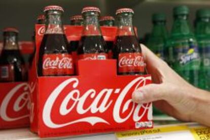 An employee arranges bottles of Coca-Cola at a store in Alexandria, Virginia in this October 16, 2012 file photo. Coca-Cola Co reported weaker-than-expected sales volumes July 17, 2013 due to ongoing economic malaise and unusually poor weather, sending its shares down nearly three percent.  REUTERS/Kevin Lamarque/Files  (UNITED STATES - Tags: BUSINESS LOGO) COCACOLA-EARNINGS/