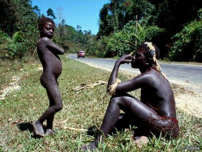 Un niño y un hombre jarawa al lado de la carretera