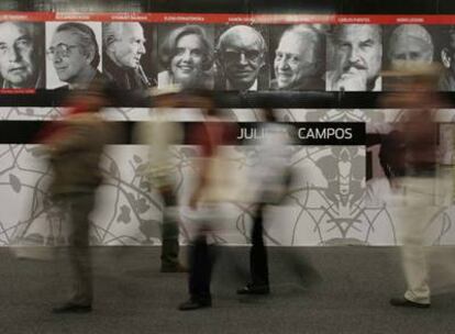 Visitantes de la Feria de Guadalajara pasean ante un panel con fotografías de escritores.