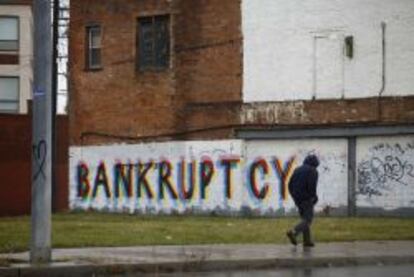 Un hombre camina delante de un grafiti en la una barriada de Detroit.