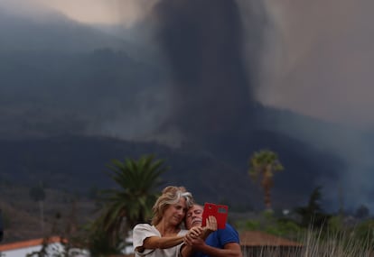 Una pareja se toma una foto en Los Llanos con la erupción del volcán de La Palma al fondo, esta mañana.