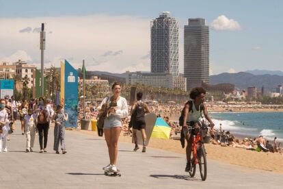 Varios ciudadanos caminan por el paseo marítimo a lo largo de la playa de San Sebastián, en Barcelona, este sábado. Tanto la megafonía de las playas como los agentes cívicos y los informadores de playas han apoyado a la policía municipal pidiendo a los usuarios que se desplazaran a otros arenales.