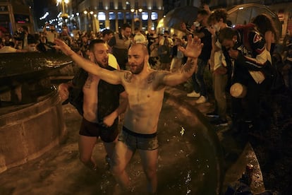 Dos jóvenes se bañan en una de las fuentes de la Puerta del Sol de Madrid tras el fin del estado de alarma.