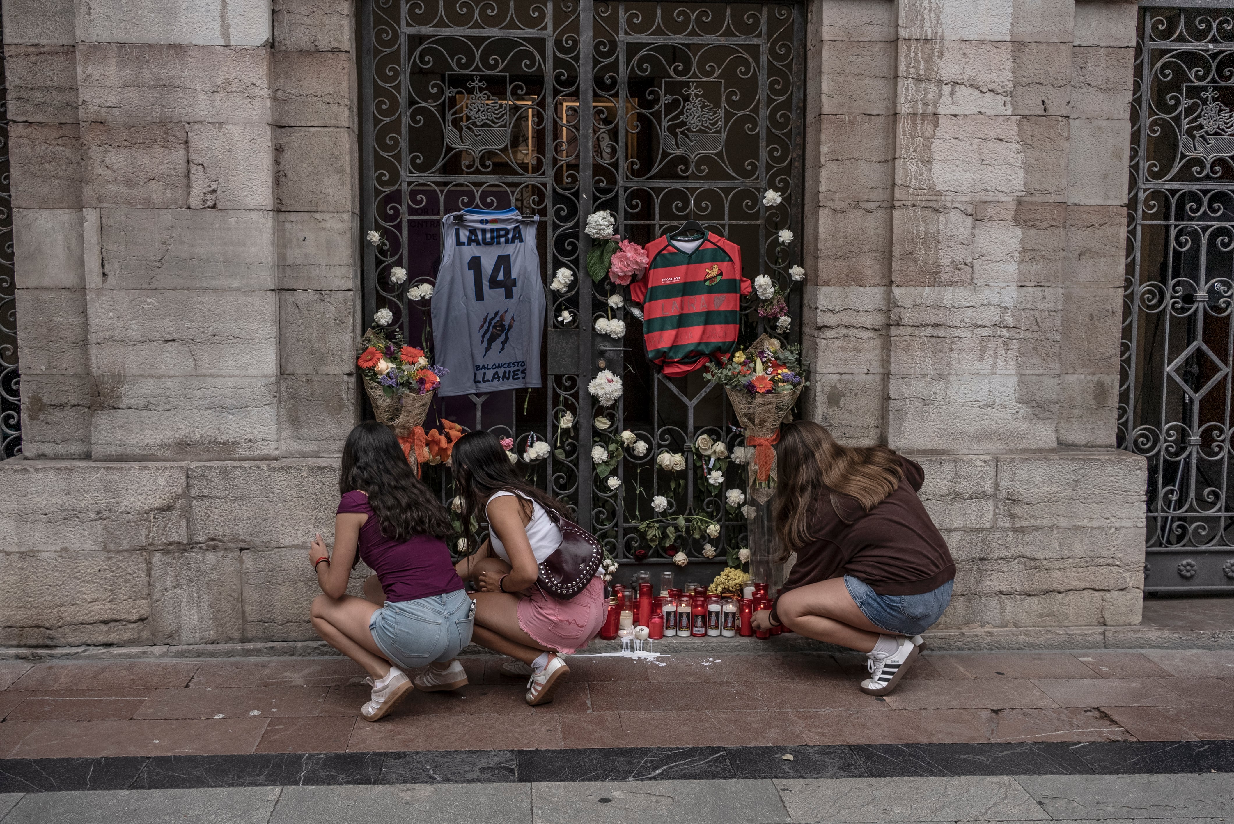 Tres chicas encienden velas durante una concentración en repulsa al asesinato machista cometido el pasado día 4 de Agosto en Llanes.