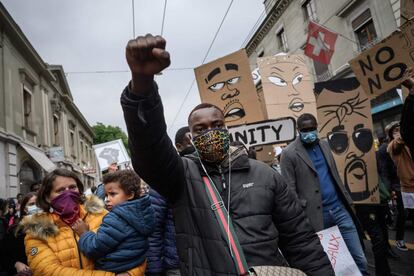 Un hombre protegido con mascarilla levanta el puño mientras participa en una manifestación contra el racismo y la brutalidad policial tras la muerte de George Floyd, en Ginebra (Suiza).