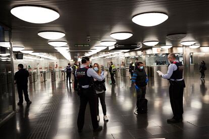 Los Mossos d'Esquadra realizan controles de movilidad en el Metro de Barcelona, donde voluntarios de Protección Civil y de Cruz Roja reparten desde primera hora de la mañana mascarillas a los usuarios para tratar de evitar nuevos contagios de coronavirus, al reanudarse en parte la actividad económica desde este martes.