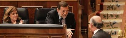 El presidente del Gobierno, Mariano Rajoy, saluda a Cristóbal Montoro en presencia de Soraya Sáenz de Santamaría en el debate sobre los presupuestos generales del Estado 2013