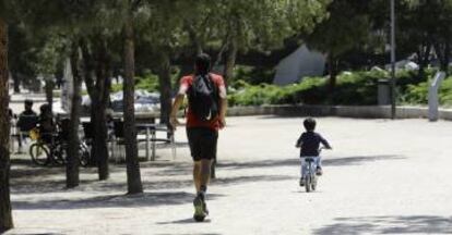 Un hombre hace deporte con un niño en bicicleta.