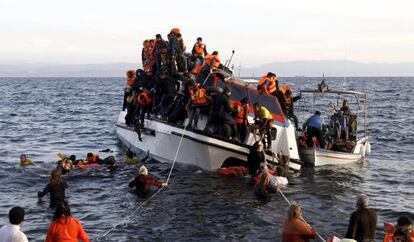 Refugiados, la mayoría sirios, tratan de abandonar un barco semihundido en la isla griega de Lesbos.