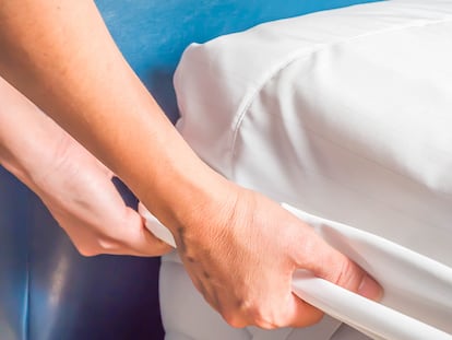 Protector de colchón siendo puesto sobre una cama.