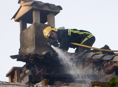 Un bombero intenta apagar el fuego desde el tejado de una de las viviendas afectadas en Membrillera.