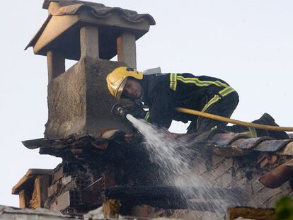 Un bombero intenta apagar el fuego desde el tejado de una de las viviendas afectadas en Membrillera.