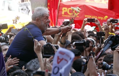 Em um momento quando era carregado, Lula segura um ramo de flores.