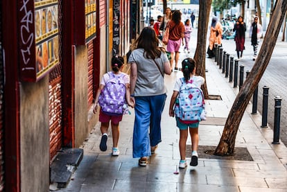 Una madre con sus hijas de camino a la escuela.