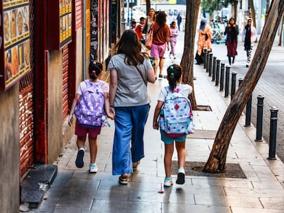 Una madre con sus hijas de camino a la escuela.