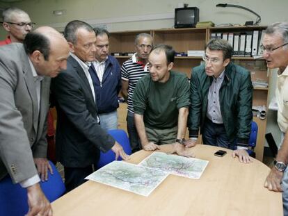 El presidente N&uacute;&ntilde;ez Feij&oacute;o y el conselleiro Hern&aacute;ndez escuchan las explicaciones de los t&eacute;cnicos ante unos mapas de la zona. / JESSICA BARCALA (EFE)