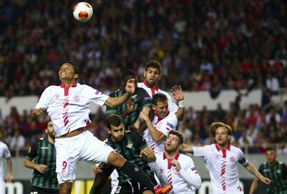 Bacca, del Sevilla salta para cabecear el balón junto a sus compañeros de equipo y los jugadores del Betis durante el partido de fútbol de Europa League en Sevilla.