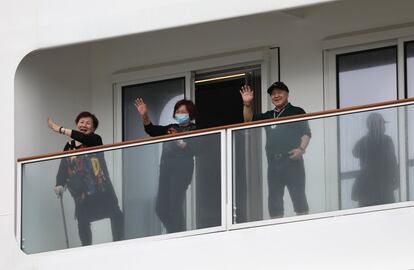 Tres pasajeros saludan desde un balcón del crucero 'World Dream'.