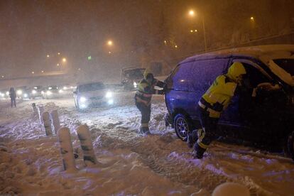 Bombeiros empurram um veículo preso pela neve na rodovia M-30 de Madri, durante a forte nevada desta sexta-feira, causada pelo temporal Filomena.