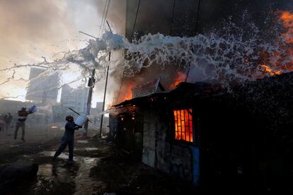 Personas intentando apagar un fuego en una casa que fue incendiada durante los disturbios en el barrio marginal de Kawangware en Nairobi (Kenia). 