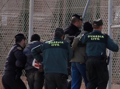 Civil Guard officers removing two migrants who had jumped the border fence in Melilla in 2014.