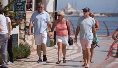 Varios turistas pasean por el paseo marítimo de la playa de Santa Ana de Arroyo de la Miel, Benalmádena (Málaga).