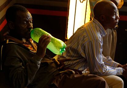 Un seguidor de la Iglesia de Gabola bebe una bebida casera de una botella de refresco durante un servicio en un bar en Orange Farm (Sudáfrica).