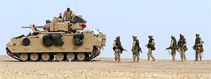 Soldados norteamericanos caminan junto a un carro de combate en unas maniobras en el desierto kuwaití, el pasado 9 de diciembre.