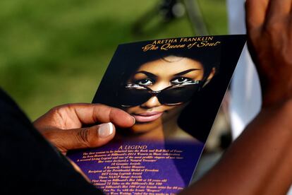 Una mujer lleva una tarjeta con una imagen de Aretha Franklin.