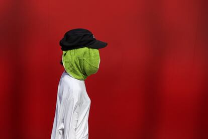 Una mujer se cubre la cabeza con una toalla debido a las altas temperaturas en Tokio, en la víspera de la ceremonia de apertura de los Juegos Olímpicos.