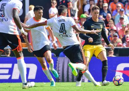 El brasileño Aderlan Santos (c) del Valencia golpea el balón ante la presencia de Fernando Torres del Atlético de Madrid.
