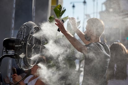 Un joven se refresca del calor con el difusor de vapor de agua de un restaurante de la calle Alcalá de Madrid, el pasado 2 de julio.