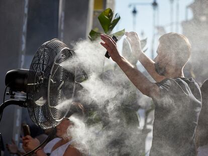 Un joven se refresca del calor con el difusor de vapor de agua de un restaurante de la calle Alcalá de Madrid, el pasado 2 de julio.