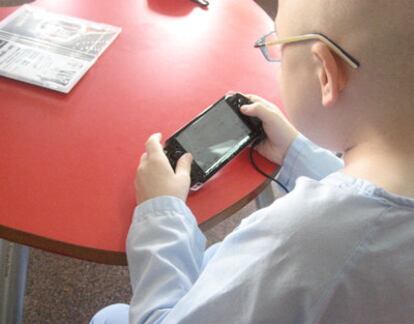 Un niño enfermo de cáncer juega con la consola PSP de Sony.