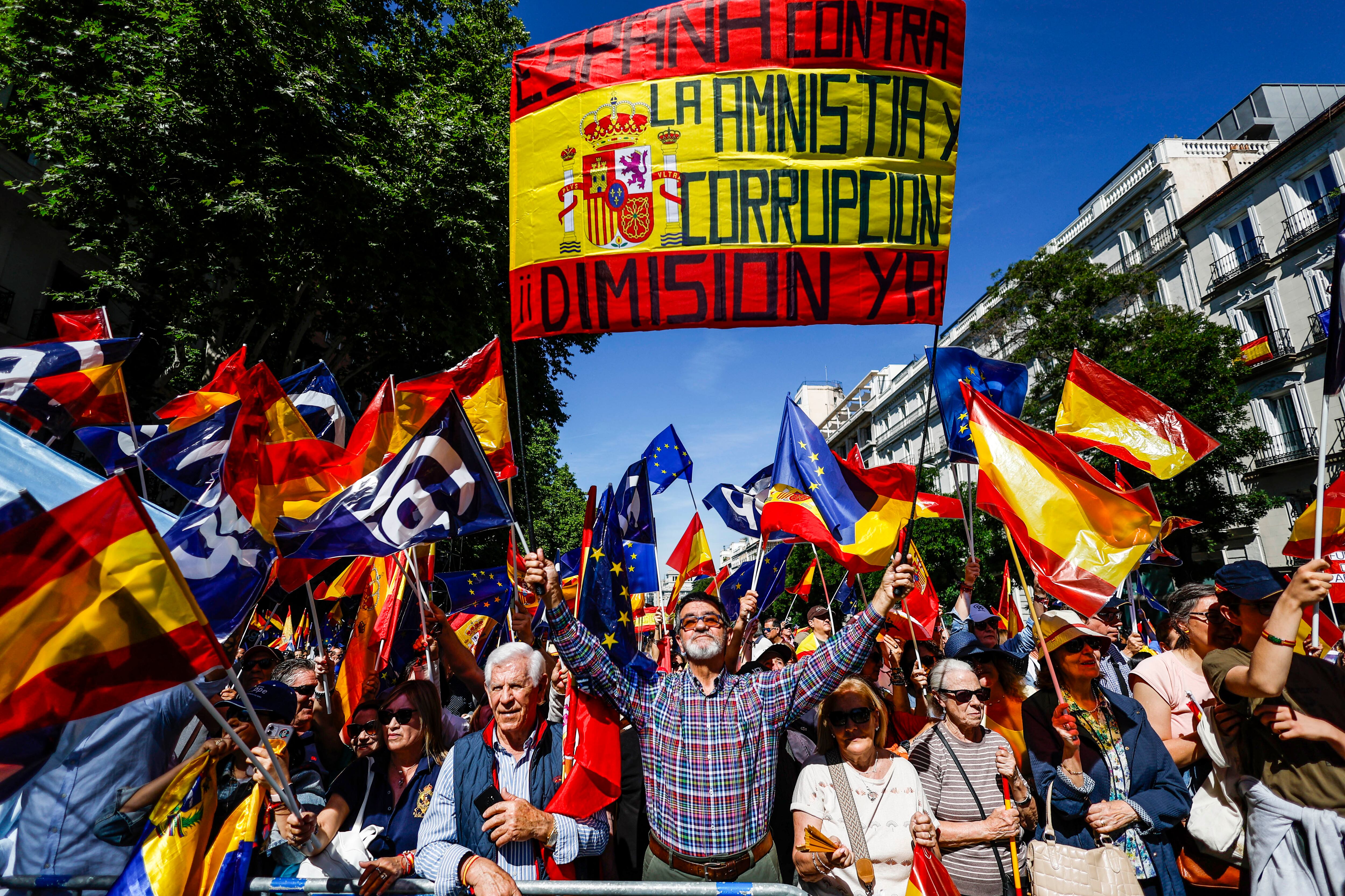 Un manifestante sujeta una bandera de España con el lema 