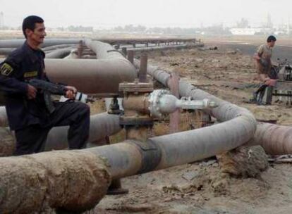 Un guardia de seguridad y un obrero, en el oleoducto de una refinería en el pueblo de Umm Quasar, al sur de Irak, ayer.