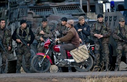 Un hombre pasa en motocicleta delante de soldados peshmerga kurdos iraquíes antes de su partida a la ciudad siria de Kobani, que ha estado bajo asalto de los extremistas del grupo Estado Islámico desde mediados de septiembre.