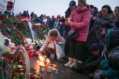 A woman lights candles at the fence next to the Crocus City Hall, on the western edge of Moscow, Russia, Saturday, March 23, 2024.