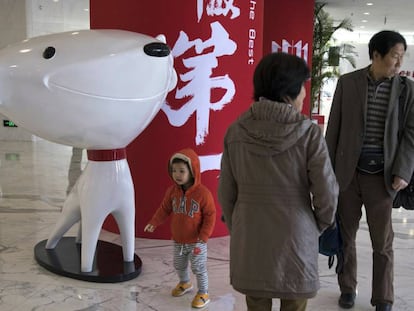 Un nuño pasea junto a la mascota del gigante chino del comercio electrónico JD.Com.