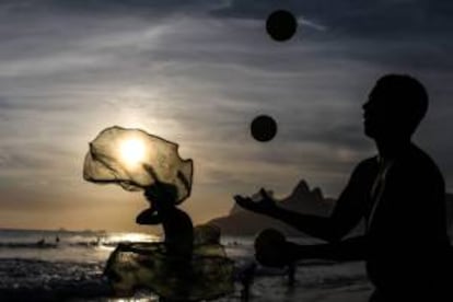 Un hombre hace malabares en la piedra de Arpoador en Río de Janeiro (Brasil). La piedra de Arpoador, que divide las playas de Copacabana e Ipanema en Río de Janeiro, es el lugar más concurrido de esta ciudad brasileña para divisar la puesta de sol.