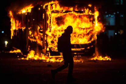 Um homem passa ao lado de um ônibus em chamas no Rio de Janeiro, após os protestos.