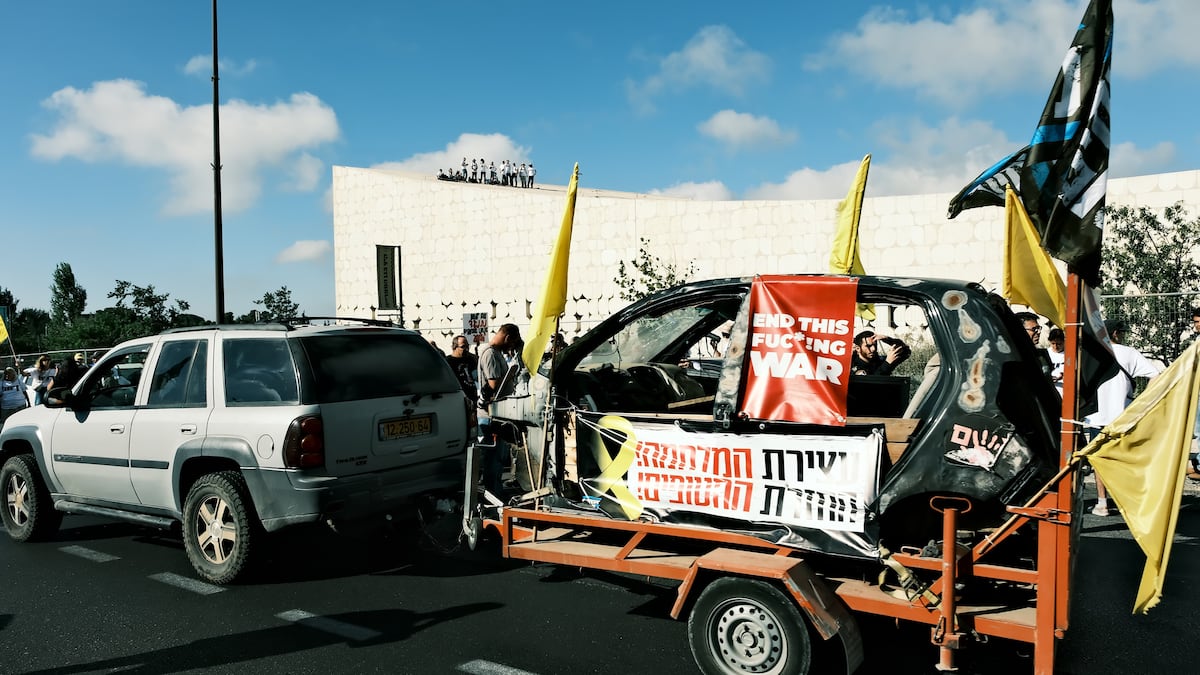 Un grupo de manifestantes prende fuego a un coche y varios contenedores frente a la residencia de Netanyahu